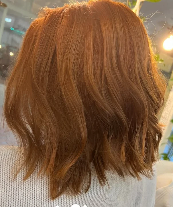 A finished copper-toned hairstyle by Kelley, viewed from behind