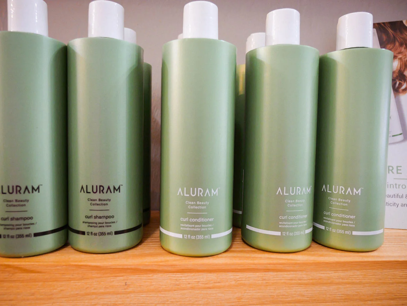 Green Aluram haircare bottles lined up on a wooden shelf
