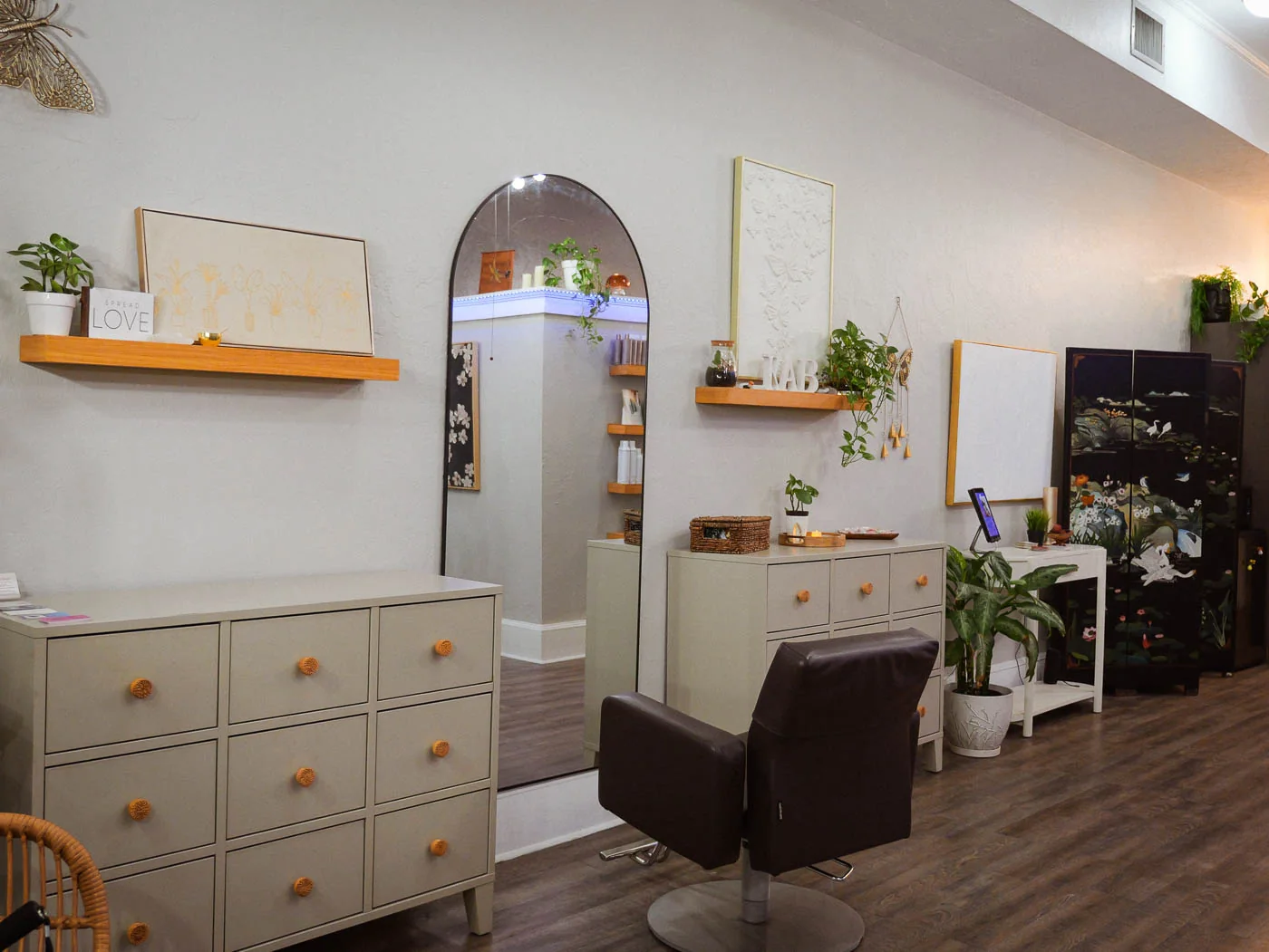 A styling chair and mirror beside a cream cabinet